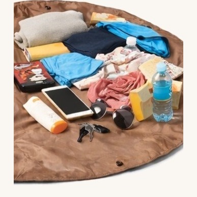 Clothes, towel, phone, keys, sunglasses, sunscreen and a bottle laid out on the open mat